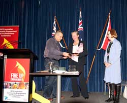 frances crown receiving the rfs award for the women's training program from rfs deputy commissioner rob rogers with carolyn chaplin (right) looking on