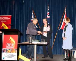 Frances Crown receiving the RFS Award for the Women's Training Program from RFS Deputy Commissioner Rob Rogers with Carolyn Chaplin (right) looking on